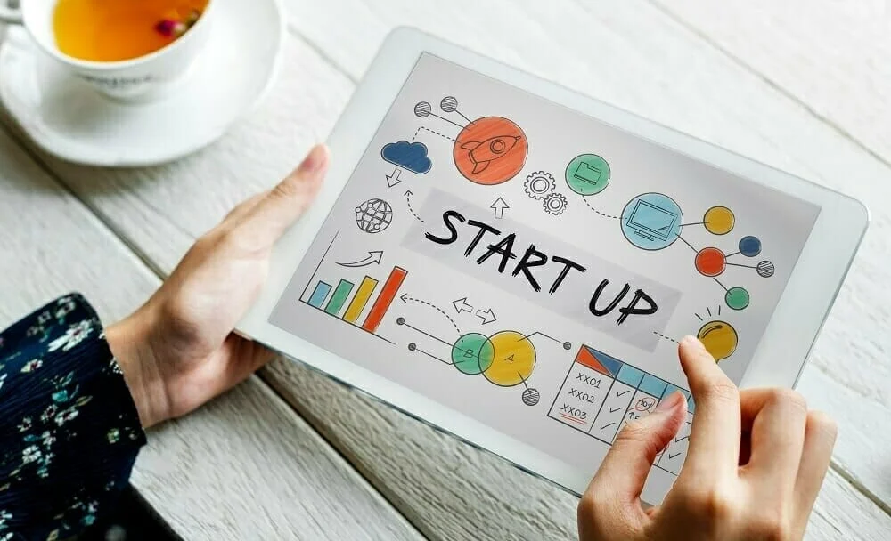 ๐ 7 Hilarious Ways Founders Desi StaPitch Ideas vs What Investors Actually Hear ๐ฐ๐ written startup on a tablet holded by a girl